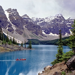 Canada, Alberta, Moraine Lake. A canoe glides across beautiful Moraine Lake in the