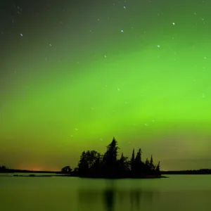 Canada, Manitoba, Whiteshell Provincial Park. Aurora borealis reflects on lake. Credit as