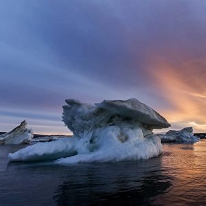 Canada, Nunavut, Territory, Setting midnight sun lights clouds above melting iceberg