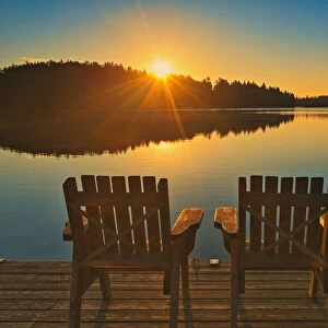 Canada, Ontario, Temagami. Muskoka chairs on Snake Island Lake dock at sunrise