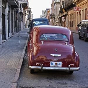 A classic old red Peugeot car parked on a street corner, probably from the 1950s