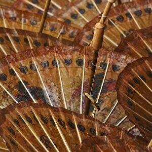 Close-up pattern of hand painted decorative umbrellas on sidewalk at market in Bo Sang