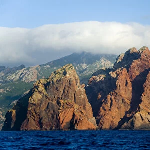 Corsica. France. Europe. Pinnacles of red granite at rise out of the sea at Punta Muchillina