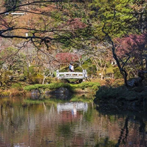 Couple walking across a bridge over a pond in the Narita Temple Garden