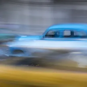 Cuba, Havana. Classic cars speed by in a blur along the streets of the city Cuba, Havana. Classic cars speed by in a blur along the streets of the city