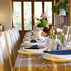 The dining room table decorated and set with flowers and decorative vegetables for dinner guests