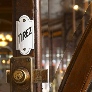 Detail of a door with a brass lock an enamel sign saying tirez (pull)