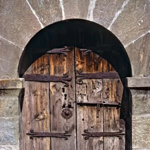 Europe, Andorra. An ancient old wooden door contrasts against a stone building in Andorra