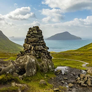 Europe, Faroe Islands. View of stone pillar overlooking the bay on the road to