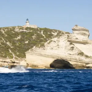 Europe, France, Corsica, Bonifacio. Boat passes Capo Pertusato lighthouse