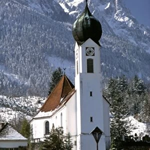 Germany, Bavaria, Obergrainau. Snow covers the mountains behind the church at Obergrainau