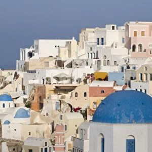 Greece, Santorini, Thira, Oia. Blue dome of Greek Orthodox church with town in the background
