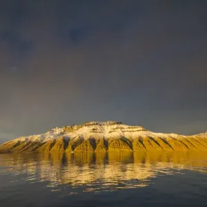 Le Groenland. Le fjord du roi Oscar. Des montagnes profondément érodées réfléchies dans l'eau calme. Le Groenland. Le fjord du roi Oscar. Des montagnes profondément érodées réfléchies dans l'eau calme.