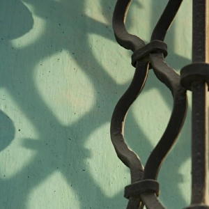 Guatemala, Antigua. Wrought-iron window grate, with shadows on turquoise wall
