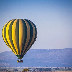 A hot-air balloon slowly traverses over the Serengeti plain