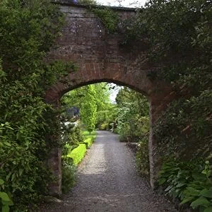 Ireland, the Dromoland Castle very green walled garden path through a brick archway