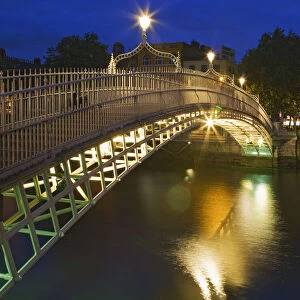 Ireland, Dublin. Ha Penny Bridge and River Liffey lit at night
