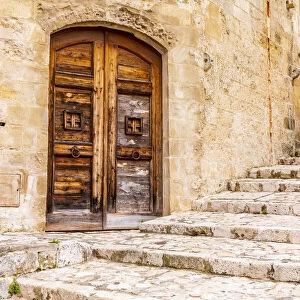 Italy, Basilicata, Province of Matera, Matera. Old wooden door in a stone wall above