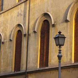 Italy, Tuscany, Lucca. Street lamppost and arched windows with wooden shutters