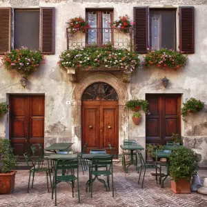 Italy, Tuscany, Pienza. Tables and chairs set up outside for outdoor dining in the town of Pienza