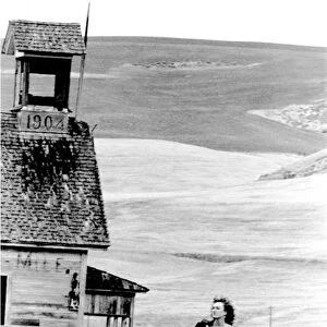 Kim Searcy walking besides a old abandoned 1904, schoolhouse in Wasco county outside The Dalles