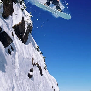 Man on a snowboard jumping off a cornice at Snowbird Resort in Little Cottonwood