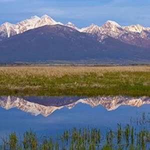 Mission Mountains cast a perfect refection in small pond at the Ninepipe WMA in the