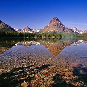 Mountains reflect into calm Two Medicine Lake in Glacier National Park in Montana
