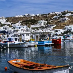 Mykonos, Greece. Orange and white boat floats in the water with other colorful boats Mykonos, Greece. Orange and white boat floats in the water with other colorful boats