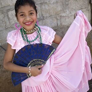 Nicaragua, Granada. Girl with fan in traditional dress after dance in Villa Esperanza barrio