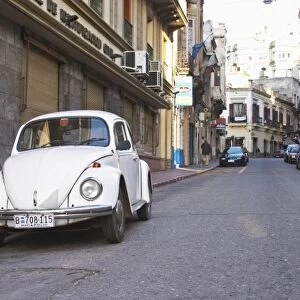 An old white Volksvagen Beetle probably from the 1960s parked on the street in the