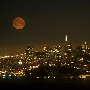 An orange full moon rises over the San Francisco cityscape