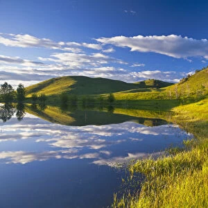 Pond reflects at days end in the Bears Paw Mountains near Havre, Montana, USA