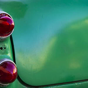 Detail of two red tail lights on classic green car in Trinidad, Cuba