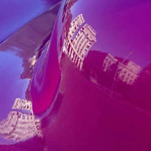 Reflection of buildings in trunk of hot pink classic American Oldsmobile in Vieja