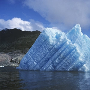 South America, Chile, San Rafael Lagoon NP. A striated, sun-touched iceberg floats