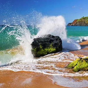 Surf crashing on rocks at Secret Beach (Kauapea Beach), Kilauea Lighthouse visible