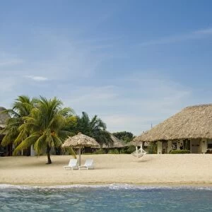 Thatched palapas, cabana and lounge chairs on beach, viewed from Caribbean Sea, Jaguar Reef Lodge