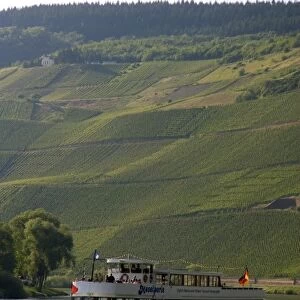 Tour boat on the Mosel River in northwest Germany with vineyards on the hillside
