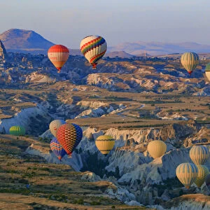 Turkey, Anatolia, Cappadocia, Goreme. Hot air balloons flying above / among rock formations