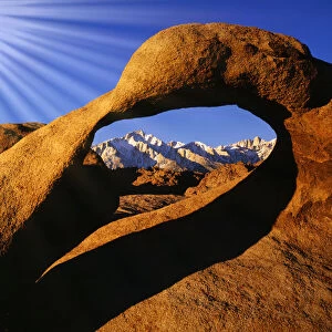 USA, California, Alabama Hills. Sun rays and granite arch that frames Lone Pine Peak