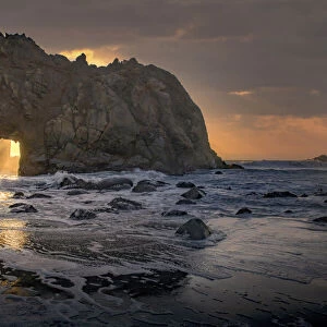 Usa, California. Sunsets gleams through this hole in the rock along the Big Sur coast