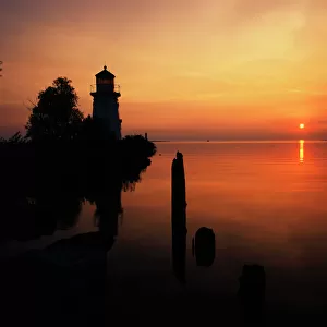 USA, Michigan, Cheboygan, View of sea and lighthouse at sunset