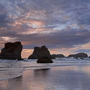 USA, Oregon, Bandon. Sunset colors clouds and silhouettes seastacks on ocean beach