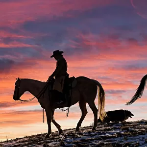 USA, Shell, Wyoming. Hideout Ranch cowgirls and dog silhouetted against sunsets sky. (PR, MR)