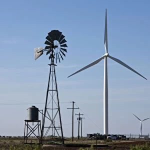 USA, Texas, Vega, Old ranch windmill and water pump beneath array of wind power generating