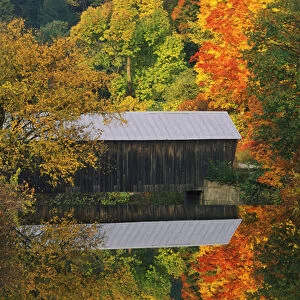 USA, Vermont. Covered bridge and autumn reflections