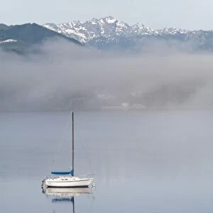 USA, Washington, Seabeck. Sailboat anchored in Hood Canal with Olympic Mountains in background