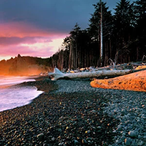 USA, Washington State, Olympic NP. Waves lap the rocky beach at sunset at Rialto Beach