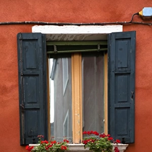 Venice, Veneto, Italy - Black wooden shutters and flowers in a planter frame a window